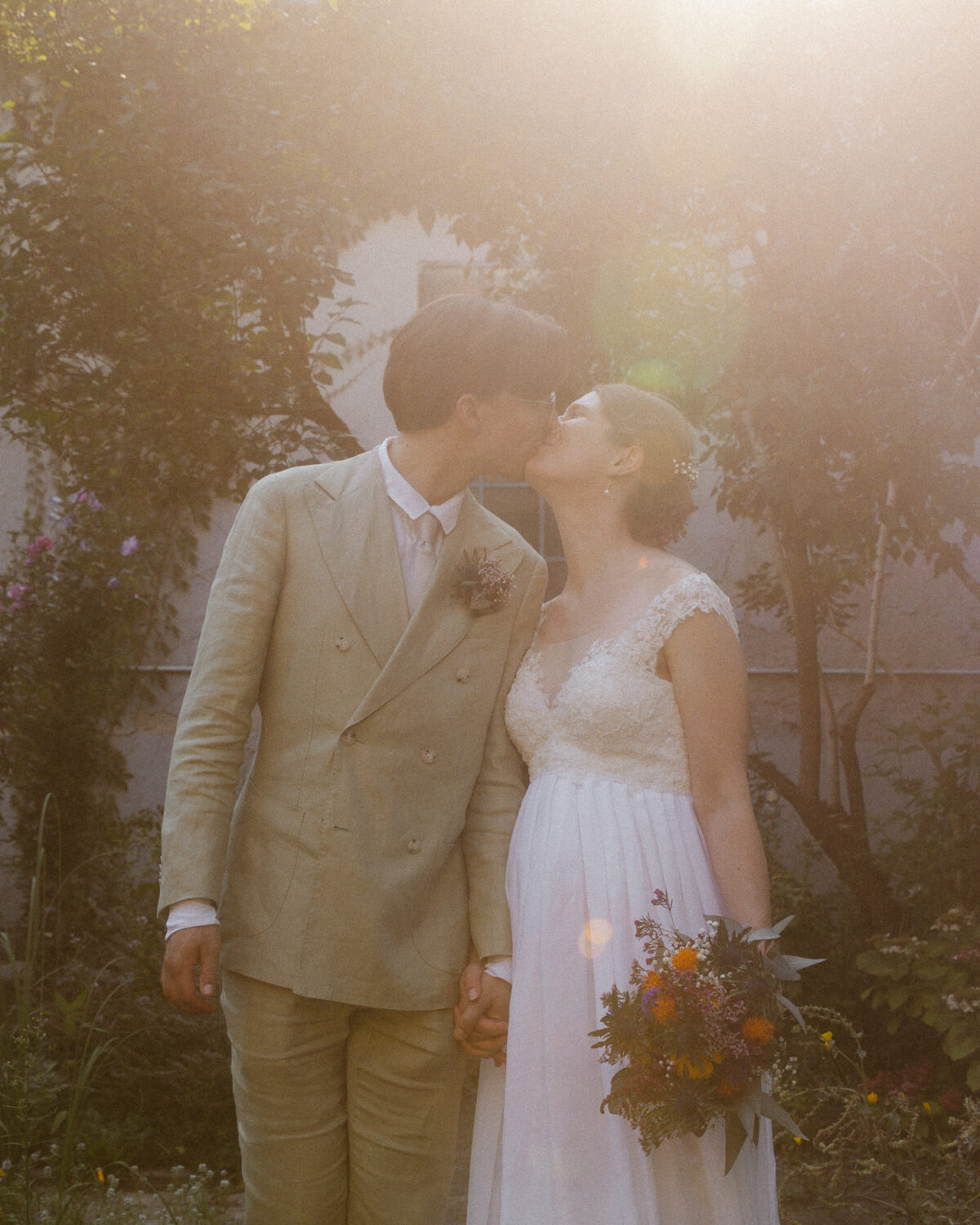 Brautpaar küsst sich im Gegenlicht bei Sommerhochzeit